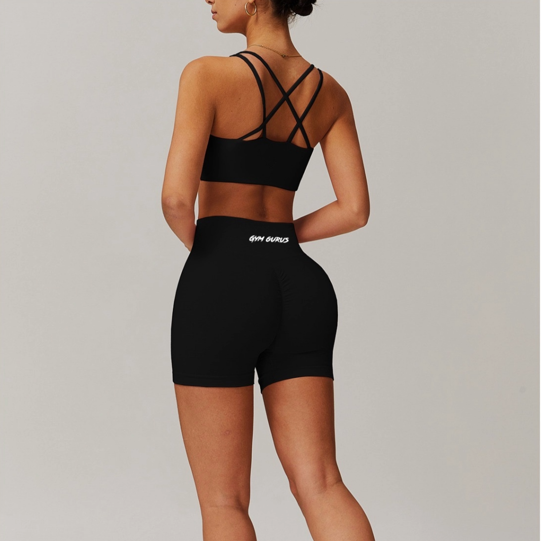 Person wearing black sports bra and shorts with visible brand logo on a light gray background