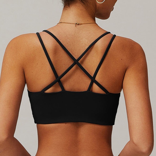 Black strappy top worn by a person on a plain background